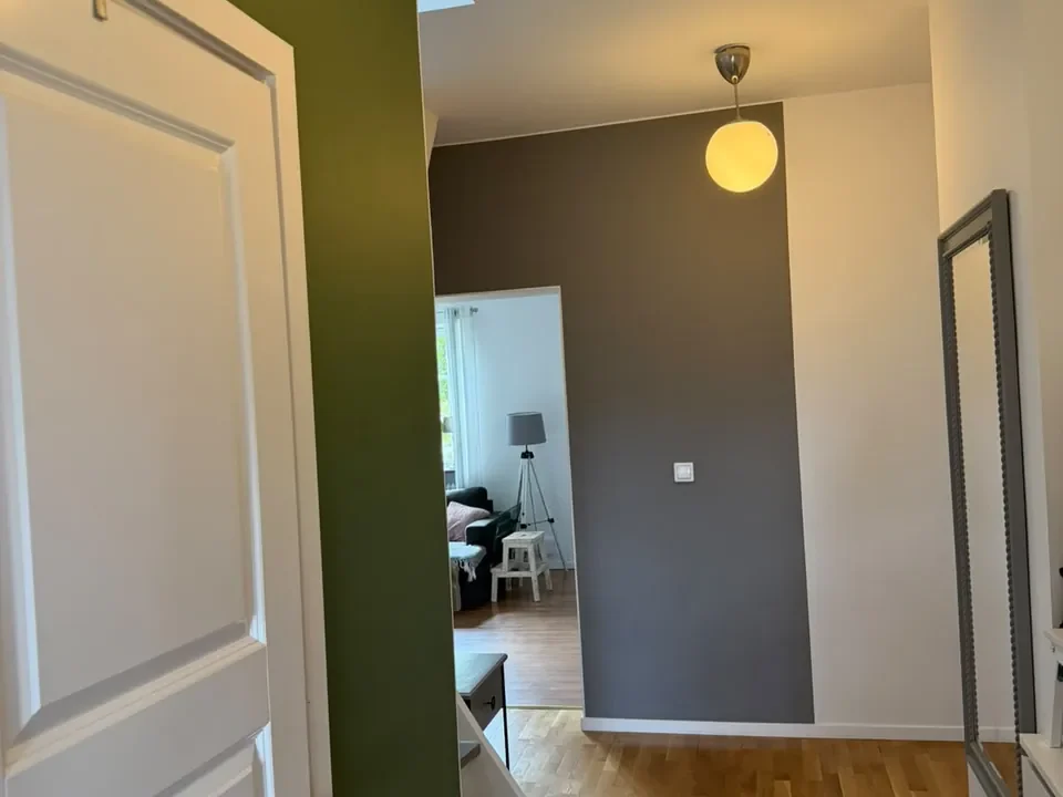 Hall i Arlöv med olivgrön accentvägg, mörkgrå vägg och vitmålade dörrar, foder och tak