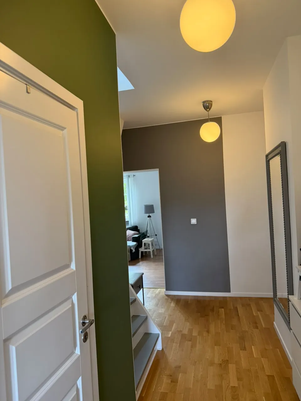 Hall i Arlöv med olivgrön accentvägg, mörkgrå vägg och vitmålade dörrar, foder och tak