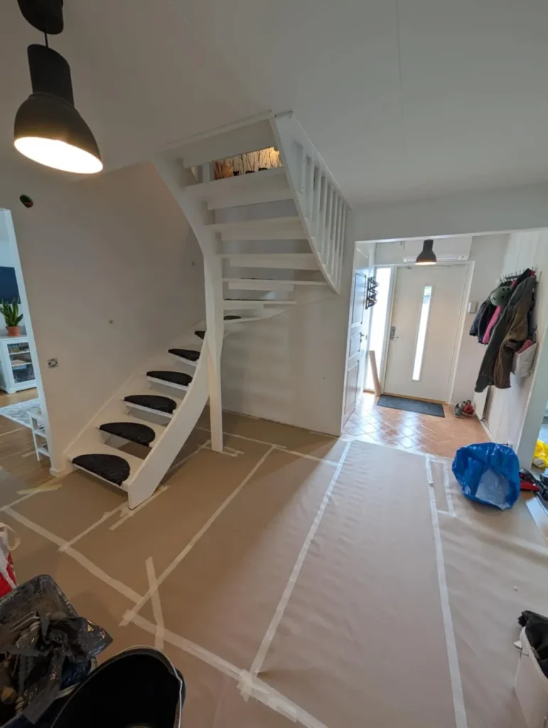 Trapphuset i Anderslöv under arbete med heltäckt och maskerat golv framför den vitmålade trappan