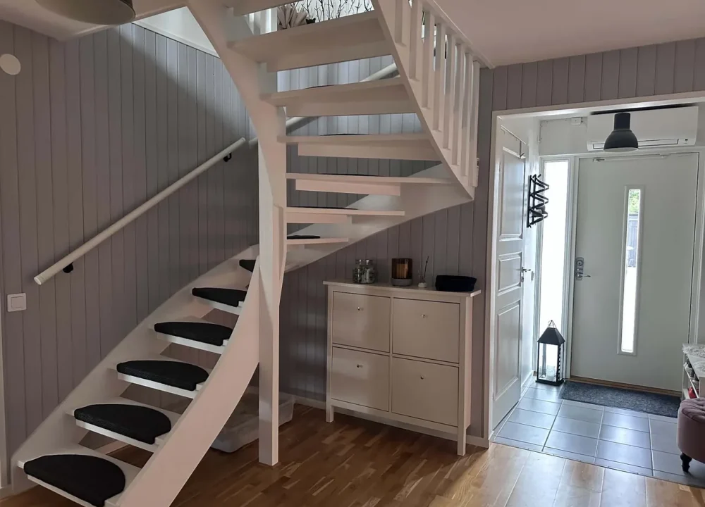 Trapphus i Anderslöv med grå liggande panel, vitmålad trappa, nytt räcke och svarta stegmattor