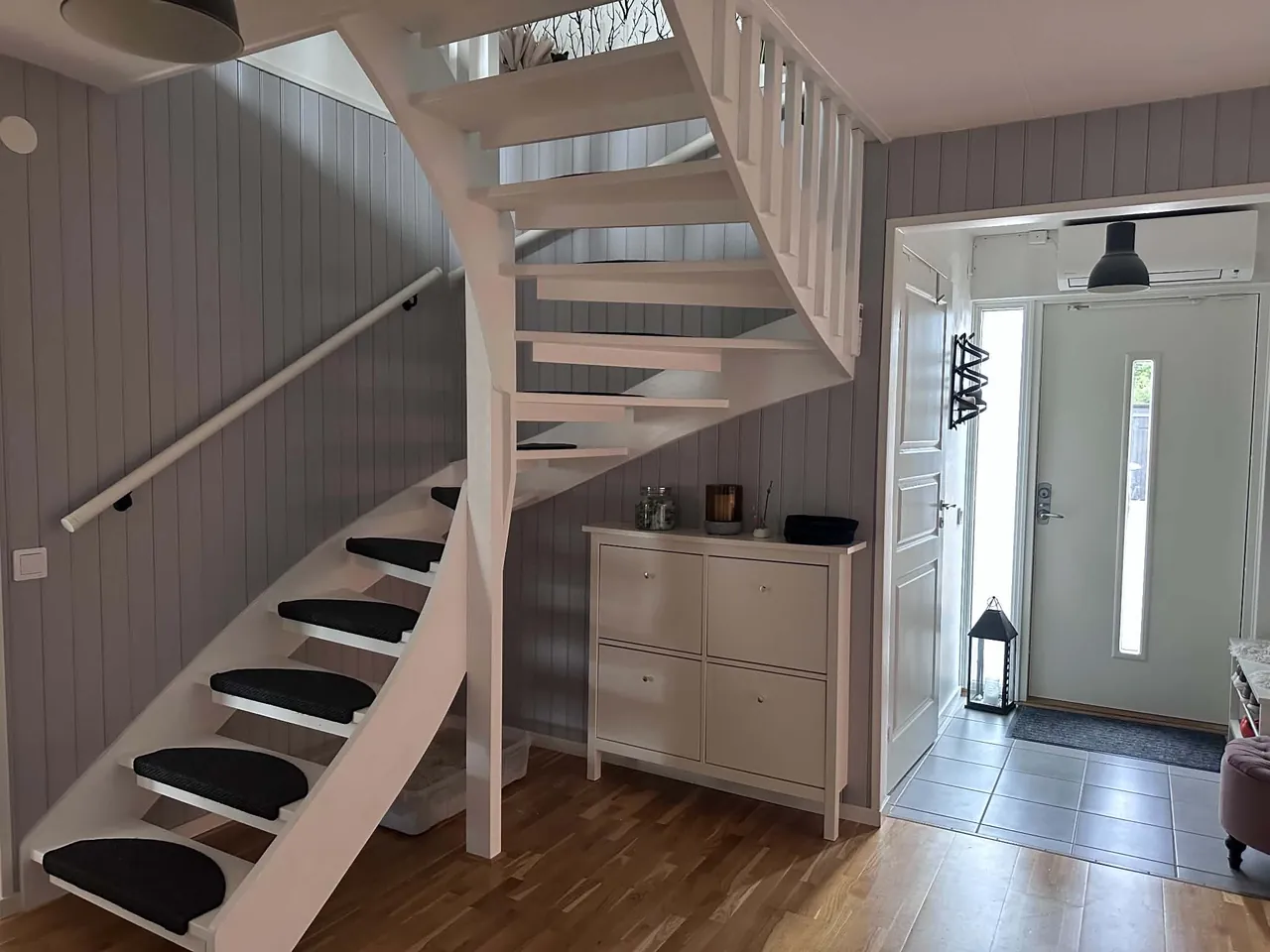 Trapphus i Anderslöv med grå liggande panel, vitmålad trappa, nytt räcke och svarta stegmattor